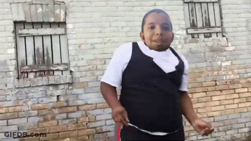 Young Boy Standing In Front Of Brick Wall GIF