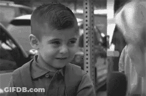 Young Boy Standing Next To Shelf Black And White GIF