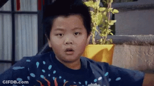 Young Boy Surprised Beside Potted Plant GIF