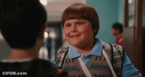 Young Boy With Backpack Talking To Another Boy In School Hallway GIF