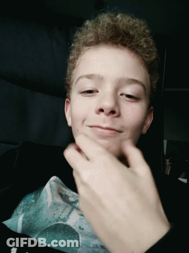 Young Boy With Curly Hair Making Face With Hand GIF