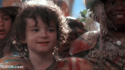 Young Boy With Curly Hair Smiling In Front Of Crowd GIF
