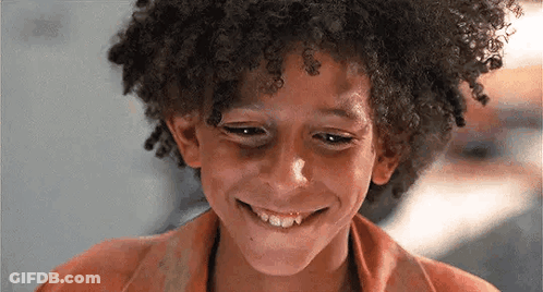 Young Boy With Curly Hair Smiling Looking Down GIF