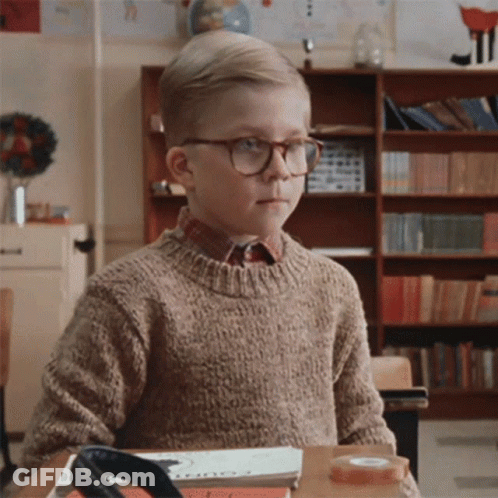Young Boy With Glasses Sitting At Desk In Classroom GIF