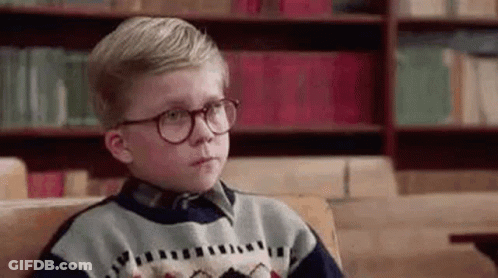 Young Boy With Glasses Sitting On Couch In Front Of Bookshelf GIF