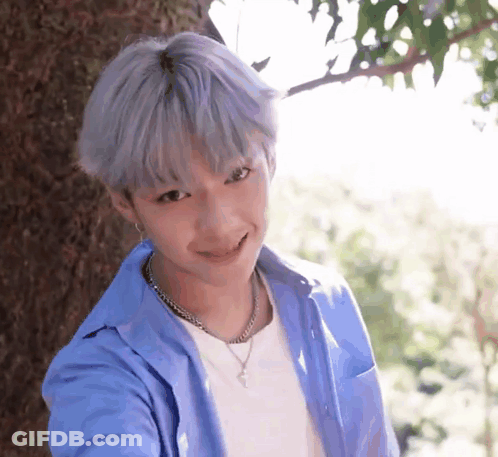 Young Boy With Gray Hair Smiling Next To Tree GIF
