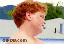 Young Boy With Red Hair And Freckles Standing In Front Of Pool GIF