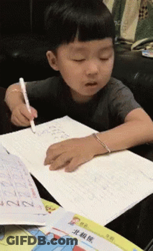 Young Boy Writing In Notebook At Table GIF