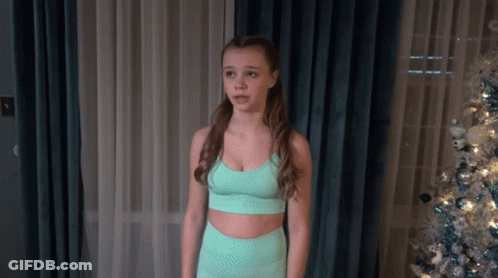 Young Girl In Green Sports Bra In Front Of Christmas Tree GIF