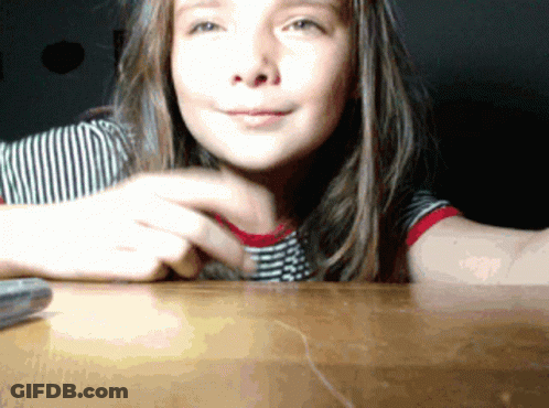 Young Girl Sitting At Table With Remote Control GIF