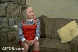 Young Girl Sitting On Couch With Yellow Pillow GIF