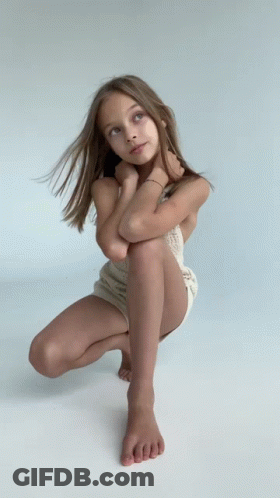 Young Girl Squatting With Legs Crossed Looking Up GIF
