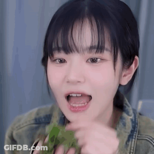 Young Girl With Bangs Eating Green Leaf GIF