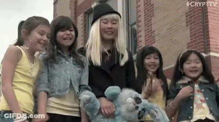 Young Girls Holding Hands Smiling In Front Of Brick Building GIF
