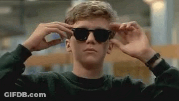 Young Man Adjusting Sunglasses In Library GIF