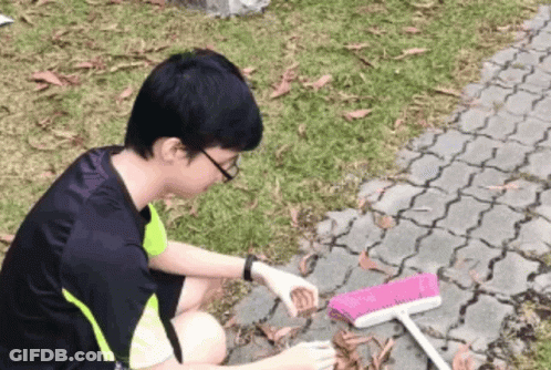 Young Man Cleaning Ground With Pink Broom GIF