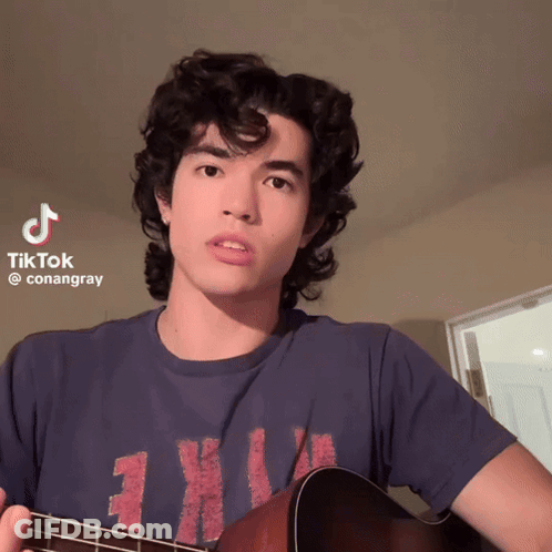 Young Man Holding Guitar With TikTok Watermark GIF