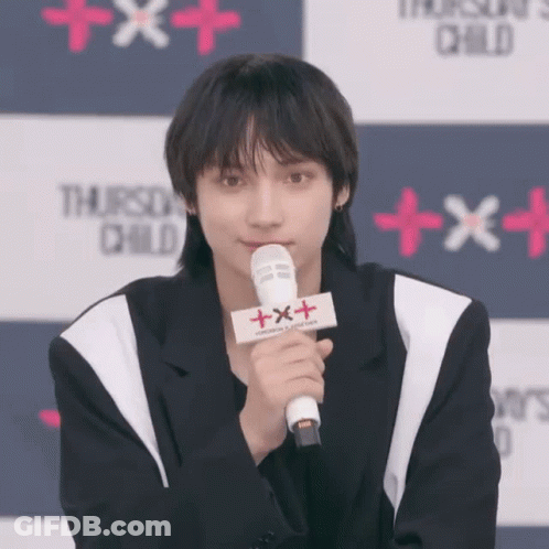 Young Man Holding Microphone With Sign Saying Txxx GIF