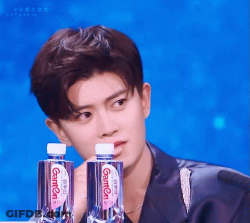 Young Man Holding Two Bottles Of Ganten Water GIF