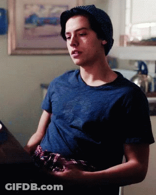 Young Man In Beanie And Blue Shirt Sitting GIF