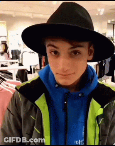 Young Man In Black Hat And Blue Jacket Looking At Camera GIF