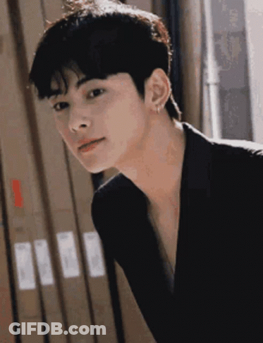 Young Man In Black Jacket And Earrings Looking At Camera GIF