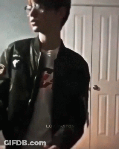 Young Man In Black Jacket And Glasses By Door GIF