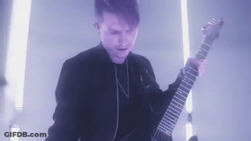 Young Man In Black Jacket Playing Guitar In Dark Room GIF