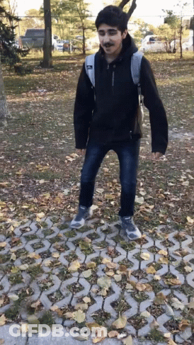 Young Man In Black Jacket With Backpack On Brick Walkway GIF