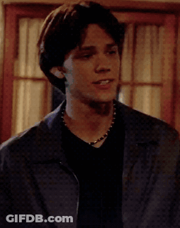 Young Man In Black Shirt And Blue Jacket At Window GIF