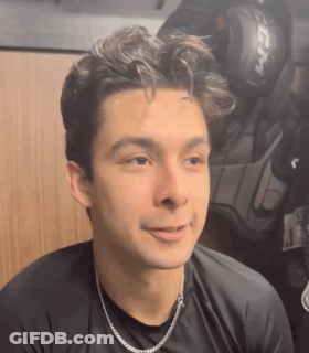 Young Man In Black Shirt And Silver Chain In Locker Room GIF