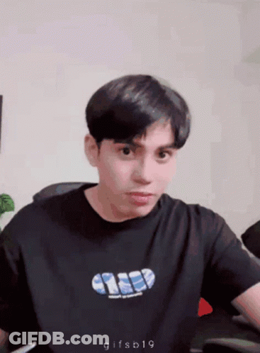 Young Man In Black Shirt Saying Gifsb19 Looking At Camera GIF