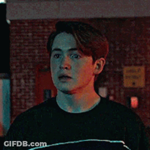 Young Man In Black T-Shirt In Front Of Brick Wall GIF