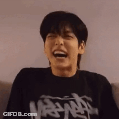 Young Man In Black T-Shirt Laughing On Couch GIF