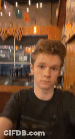 Young Man In Black T-Shirt Sitting In Restaurant GIF