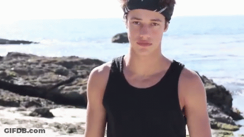 Young Man In Black Tank Top And Headband On Beach GIF