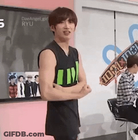 Young Man In Black Tank Top Arms Crossed In Front Of Pink Wall GIF