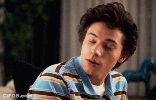 Young Man In Blue And Brown Striped Shirt Looking At Camera GIF