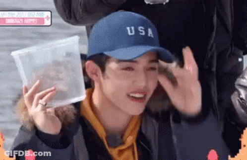 Young Man In Blue Hat Holding Plastic Container GIF