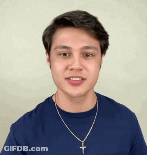 Young Man In Blue Shirt And Necklace Making Face GIF