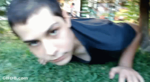 Young Man In Blue Shirt Doing Push Ups In Grass GIF