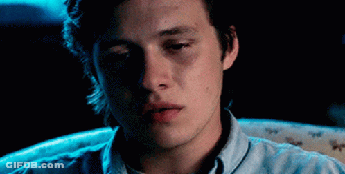 Young Man In Blue Shirt Looking At Camera In Dark GIF