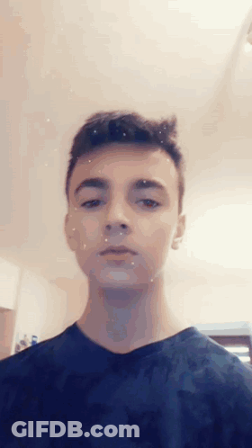 Young Man In Blue Shirt Looking At Camera GIF