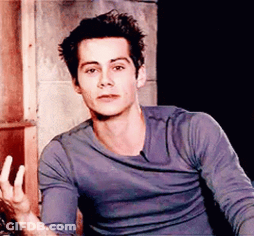 Young Man In Blue Shirt Sitting In Front Of Brick Wall GIF
