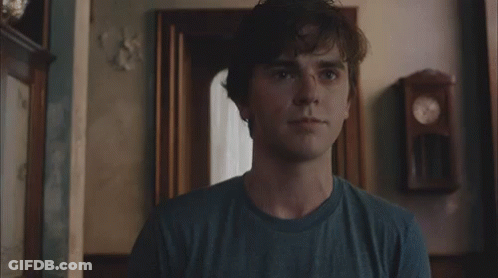 Young Man In Blue Shirt Standing In Front Of Clock GIF