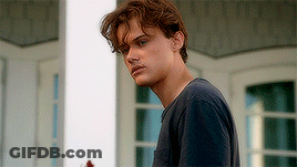 Young Man In Blue Shirt Standing In Front Of Window GIF