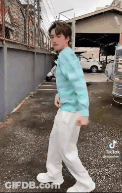 Young Man In Blue Sweater And White Pants On Sidewalk GIF