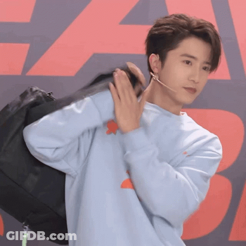 Young Man In Blue Sweater Holding Black Bag GIF