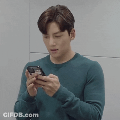 Young Man In Blue Sweater Looking At Cell Phone GIF