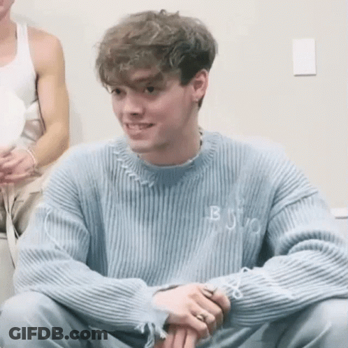Young Man In Blue Sweater Smiling With Folded Hands GIF